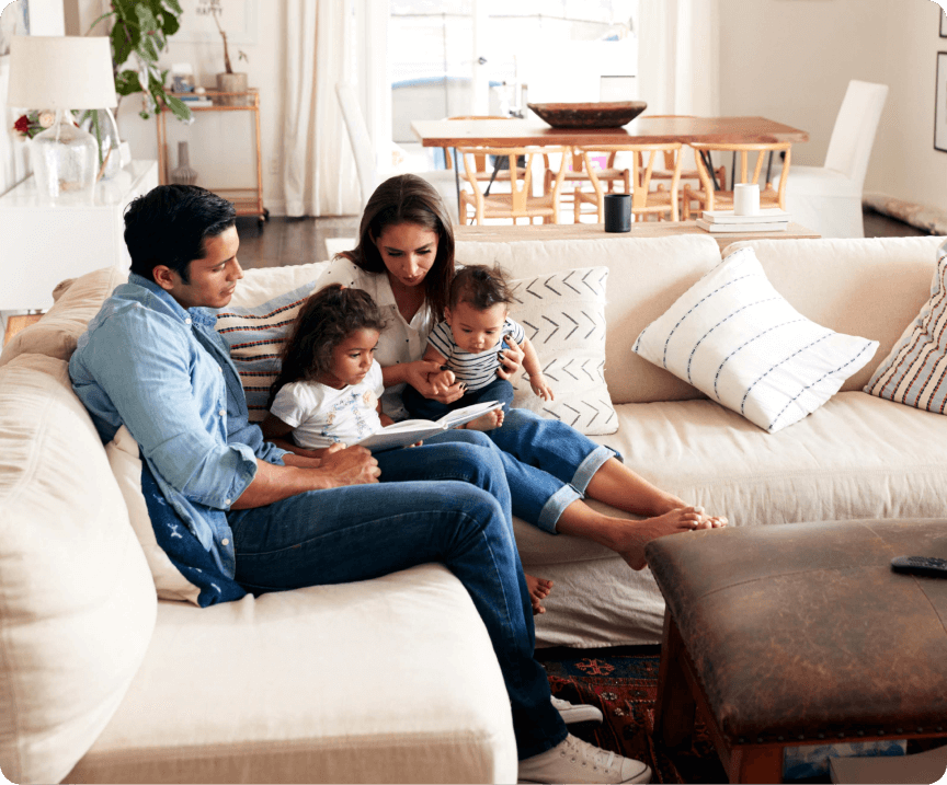 A family sitting on a couch together reading a book