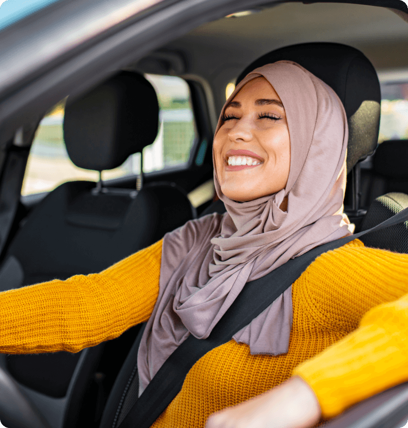 Young woman in a headscarf smiling in her car